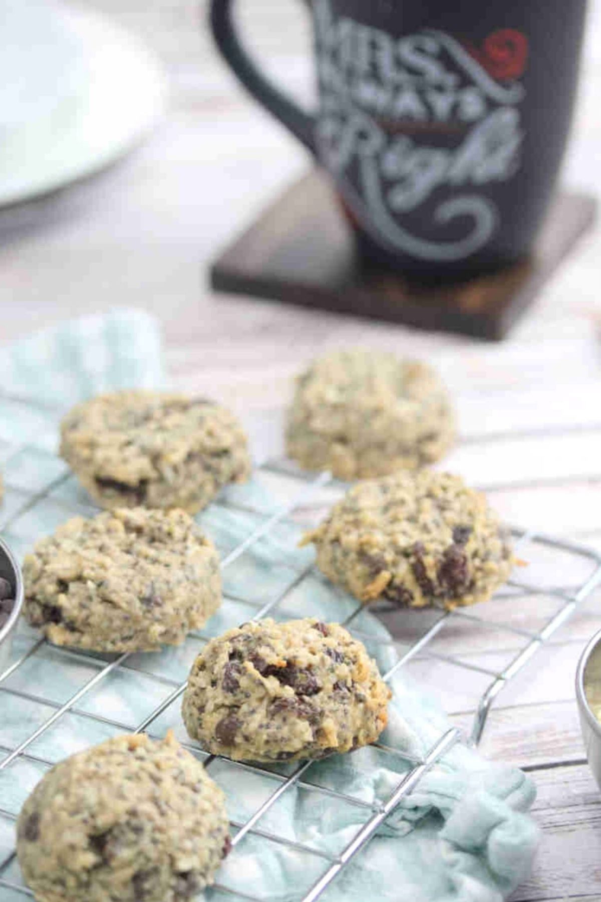 Nut-free breakfast cookies on a cooling rack on a blue linen with plates and chocolate chips around them.