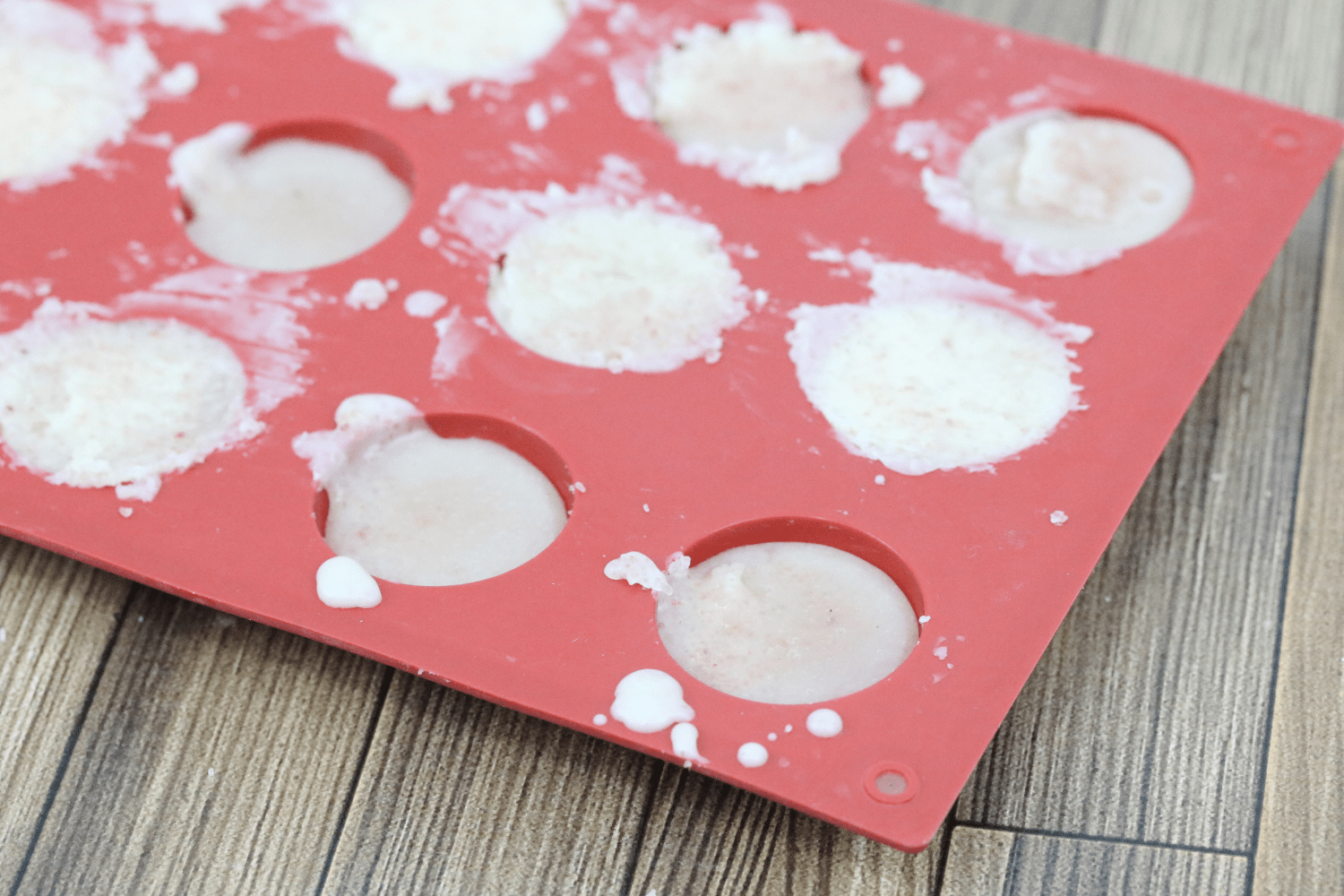 Red silicone mold with DIY salt lotion bar mixture filling the small circles