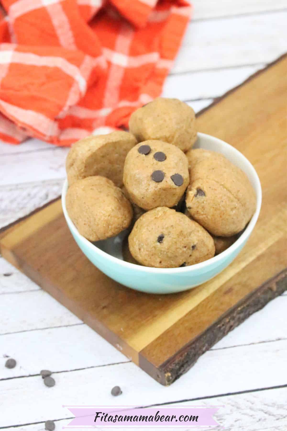 paleo cookie dough ball being held between fingers with more in a bowl