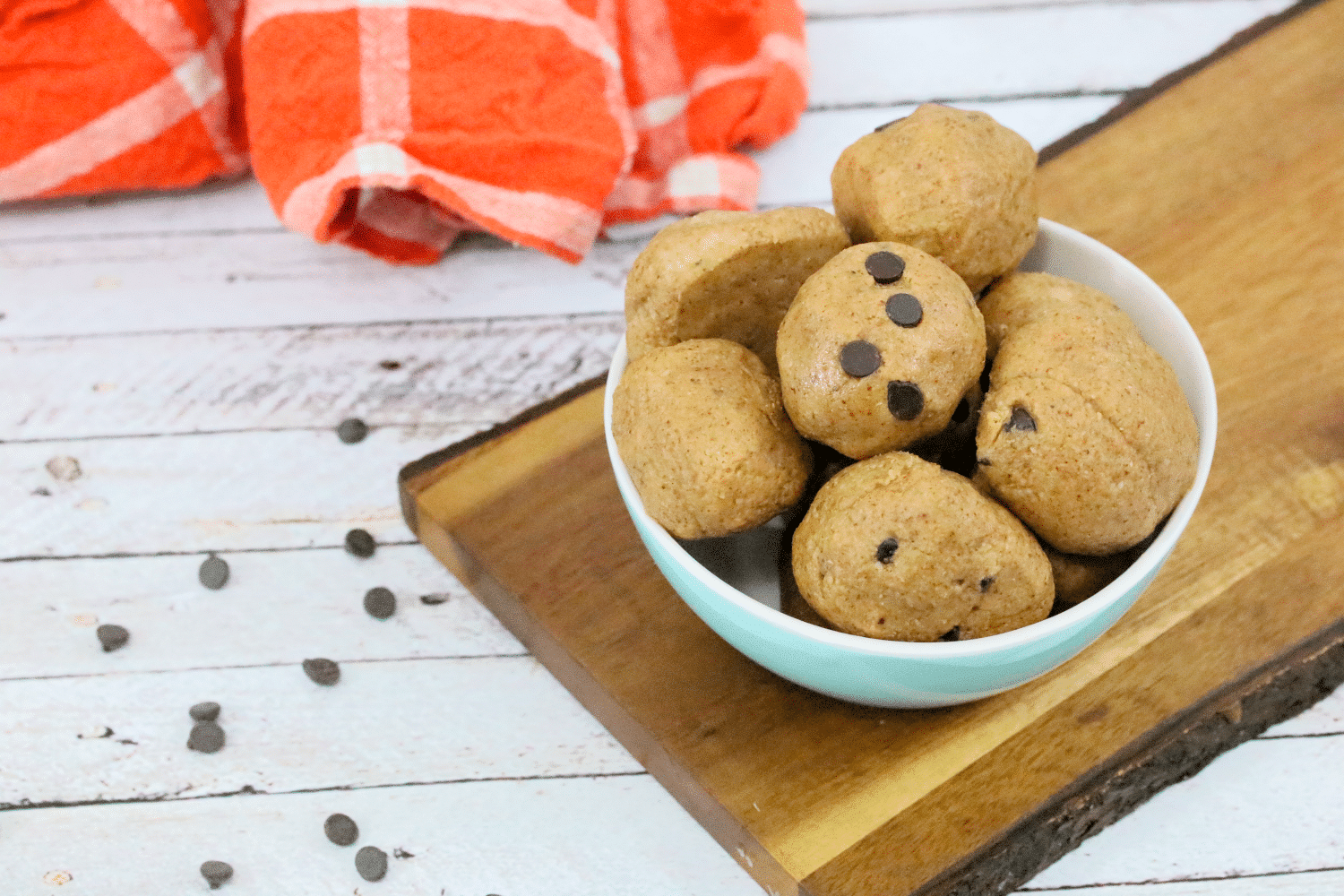 paleo cookie dough ball being held between fingers with more in a bowl