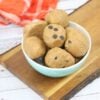 paleo cookie dough ball being held between fingers with more in a bowl