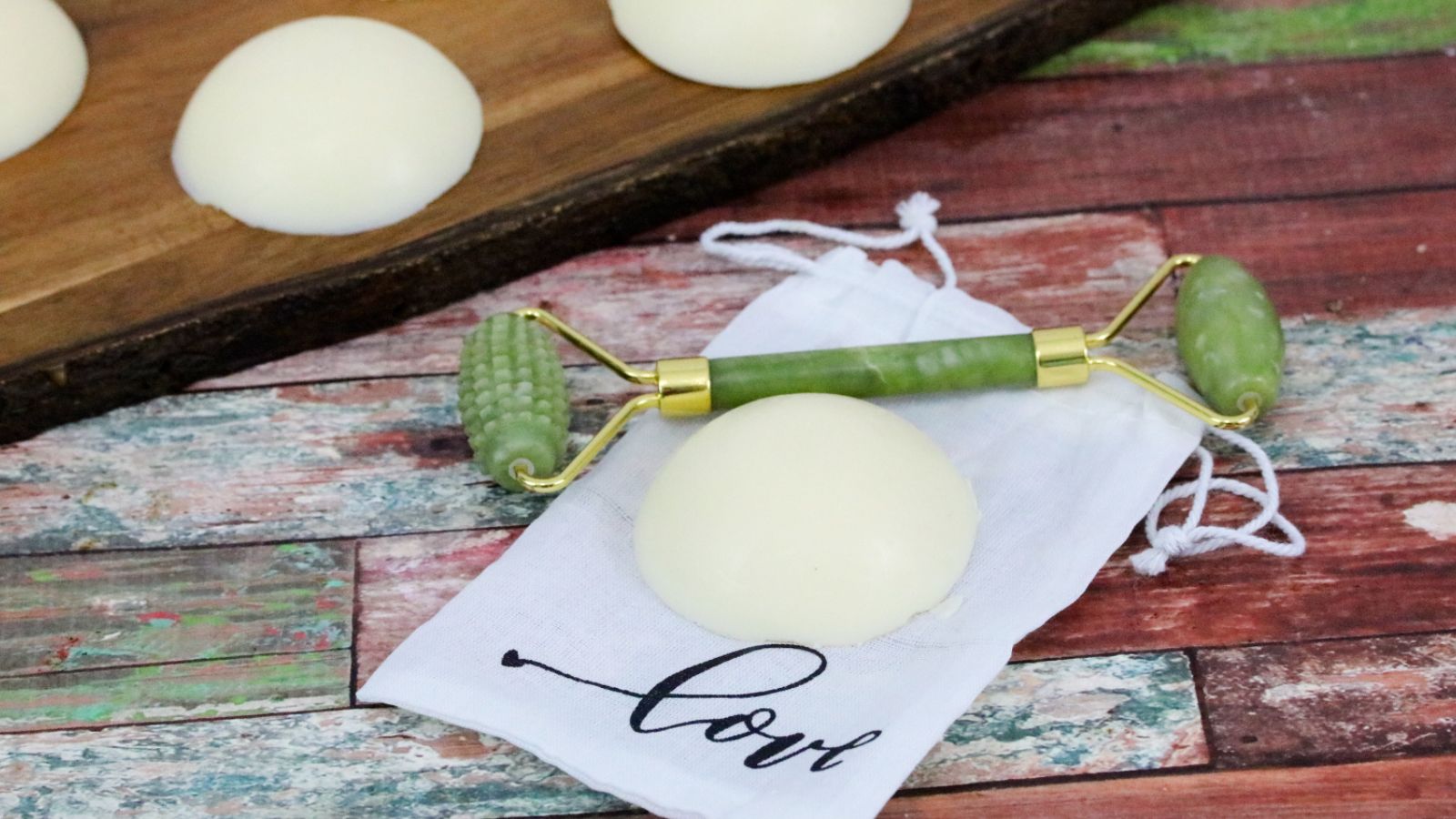 DIY lotion bars on a white napkin with a face roller and more lotion bars behind it.