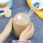 Featured image with text: gut-healing chocolate smoothie in a glass with toddler hands holding it
