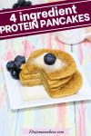 Pin image with text: healthy protein pancakes stacked with blueberries beside them on a white plate and syrup and berries behind them