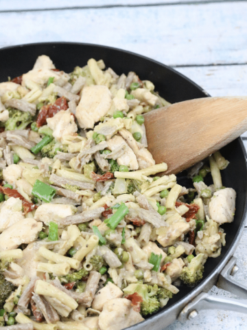 Dairy-free chicken alfredo pasta in a black pan with a wooden spoon