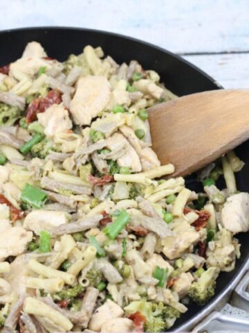 Cast iron pan with noodles, chicken, broccoli and sundried tomatoes in a creamy alfredo sauce