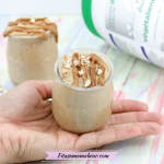 A hand holding a mini jar with caramel protein fluff topped with caramel drizzle