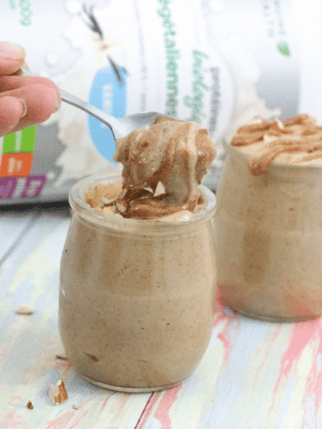 Two mini mason jars with salted caramel protein fluff the front jar with a spoonful being taken out