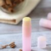 Pink lip balm tube with more behind it and pieces of chopped cinnamon sticks around it