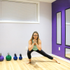 Woman in green shirt and black pants performing a squat variation