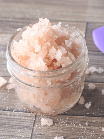 homemade honey lip scrub in a small mason jar with pink salt around it