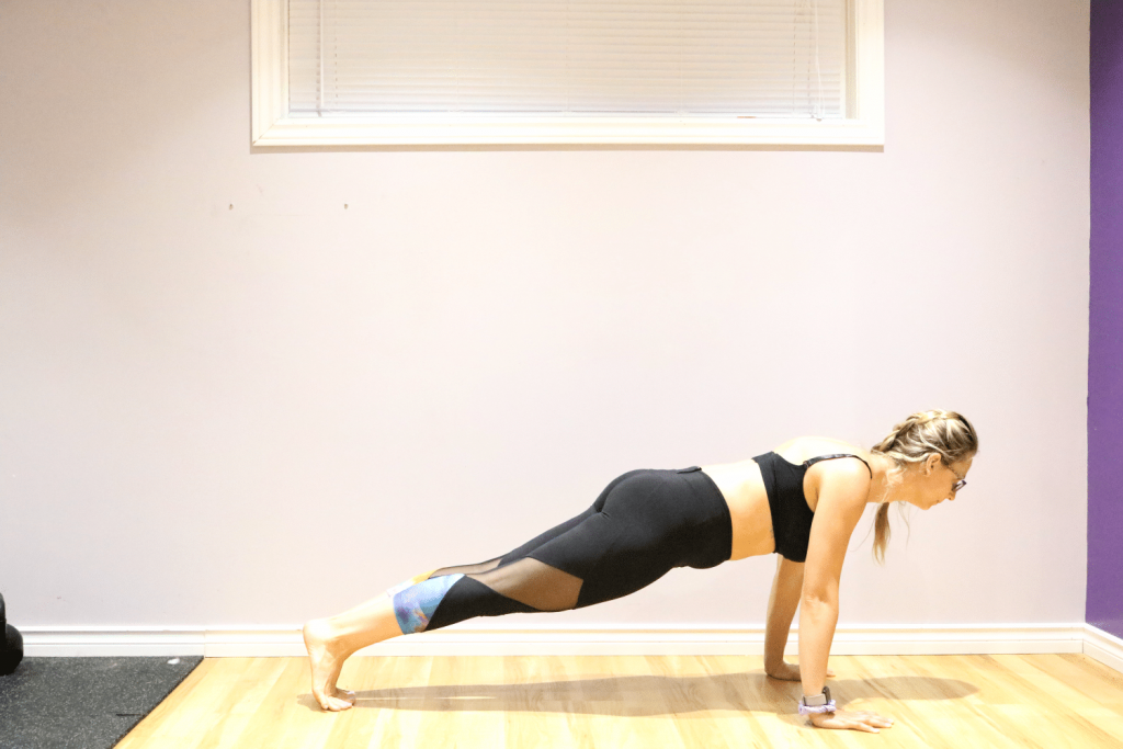 Woman in black sports bra and pants in plank position