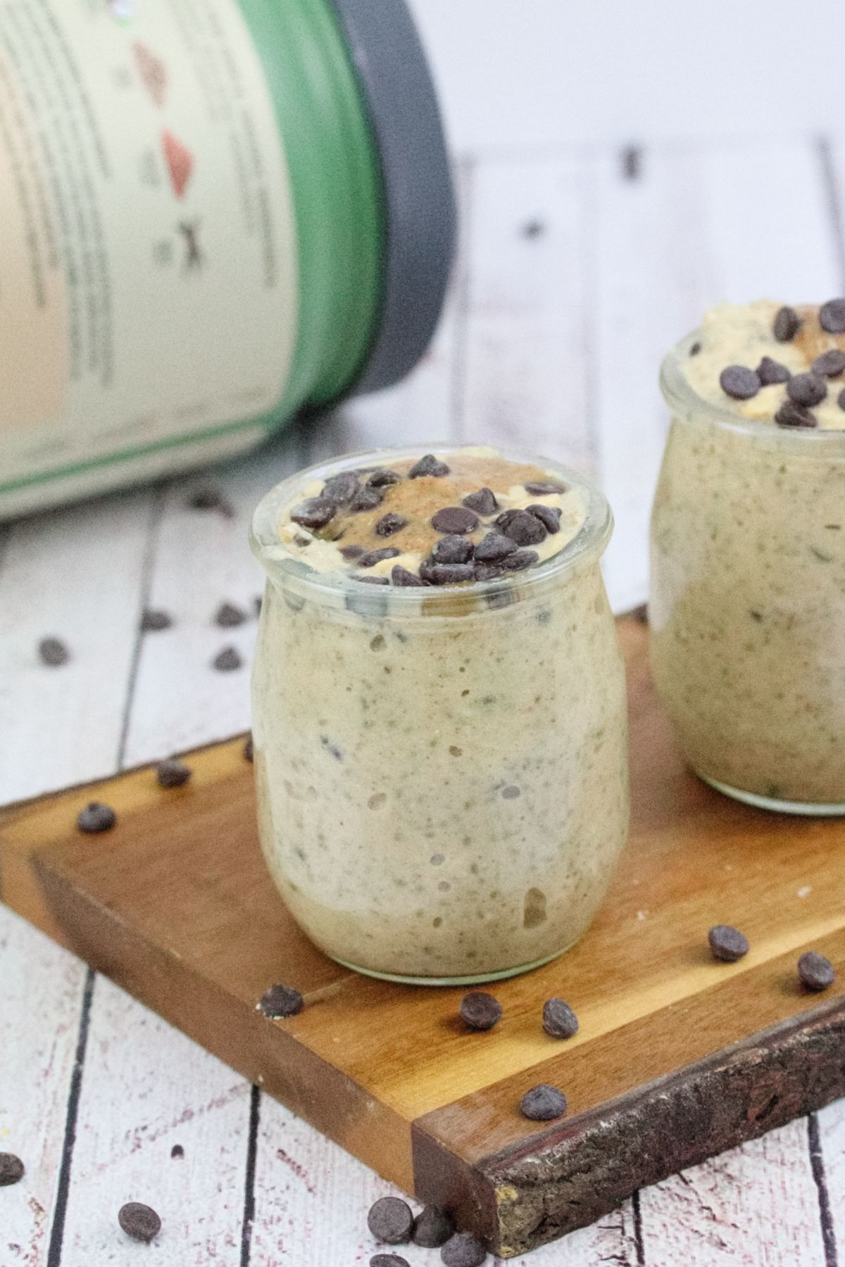 Three mason jars filled with high protein cookie dough overnight oats topped with chocolate chips on a wooden cutting board.