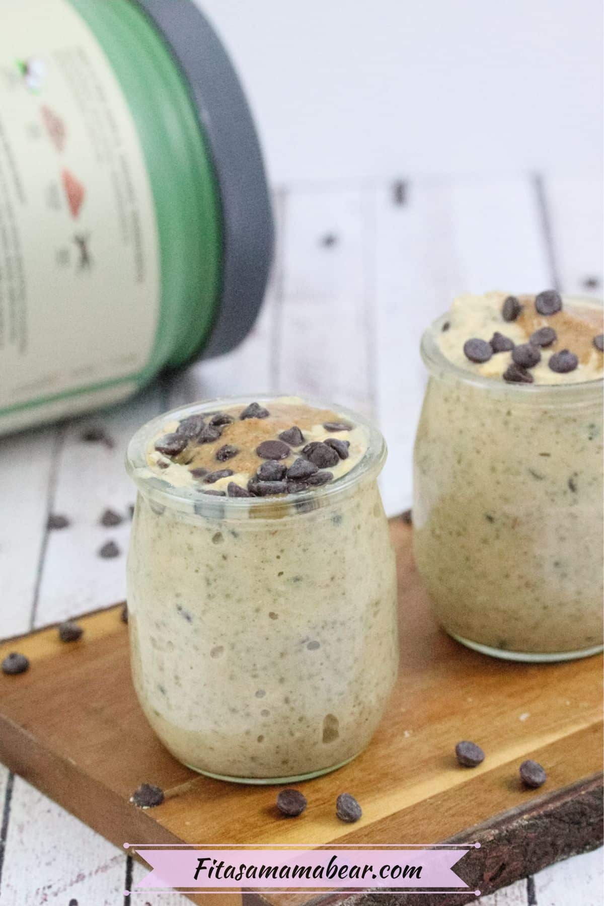 Three mason jars filled with high protein cookie dough overnight oats topped with chocolate chips on a wooden cutting board