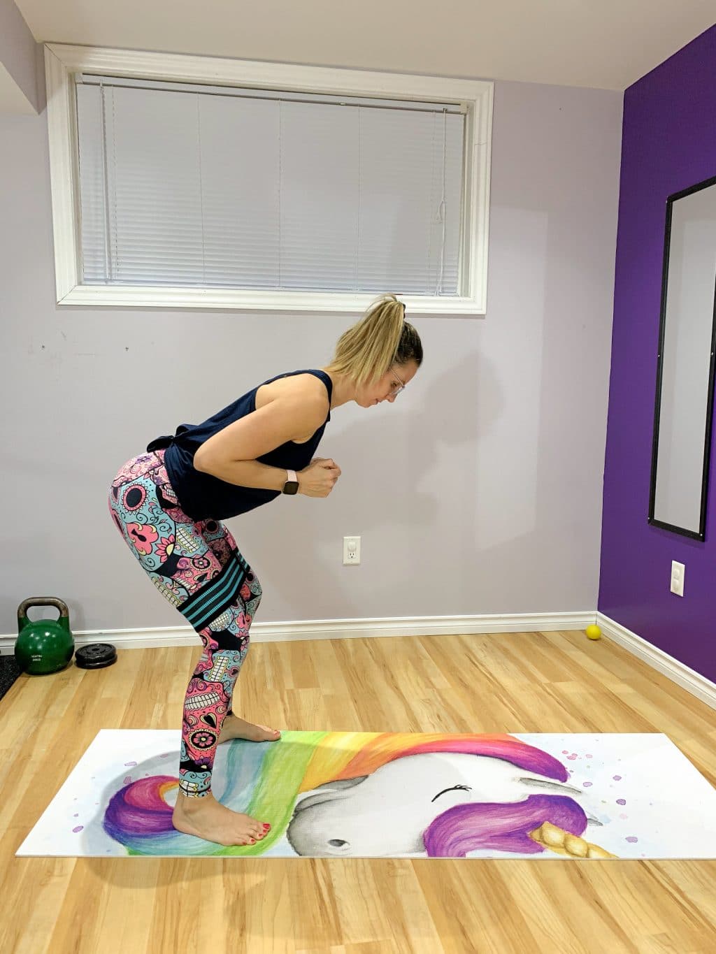 Woman in bright workout clothes on a unicorn yoga mat performing a sumo walk with a mini loop