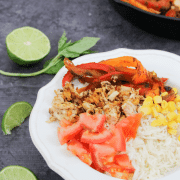chicken fajita burrito bowl on rice in a white bowl with lime on the side