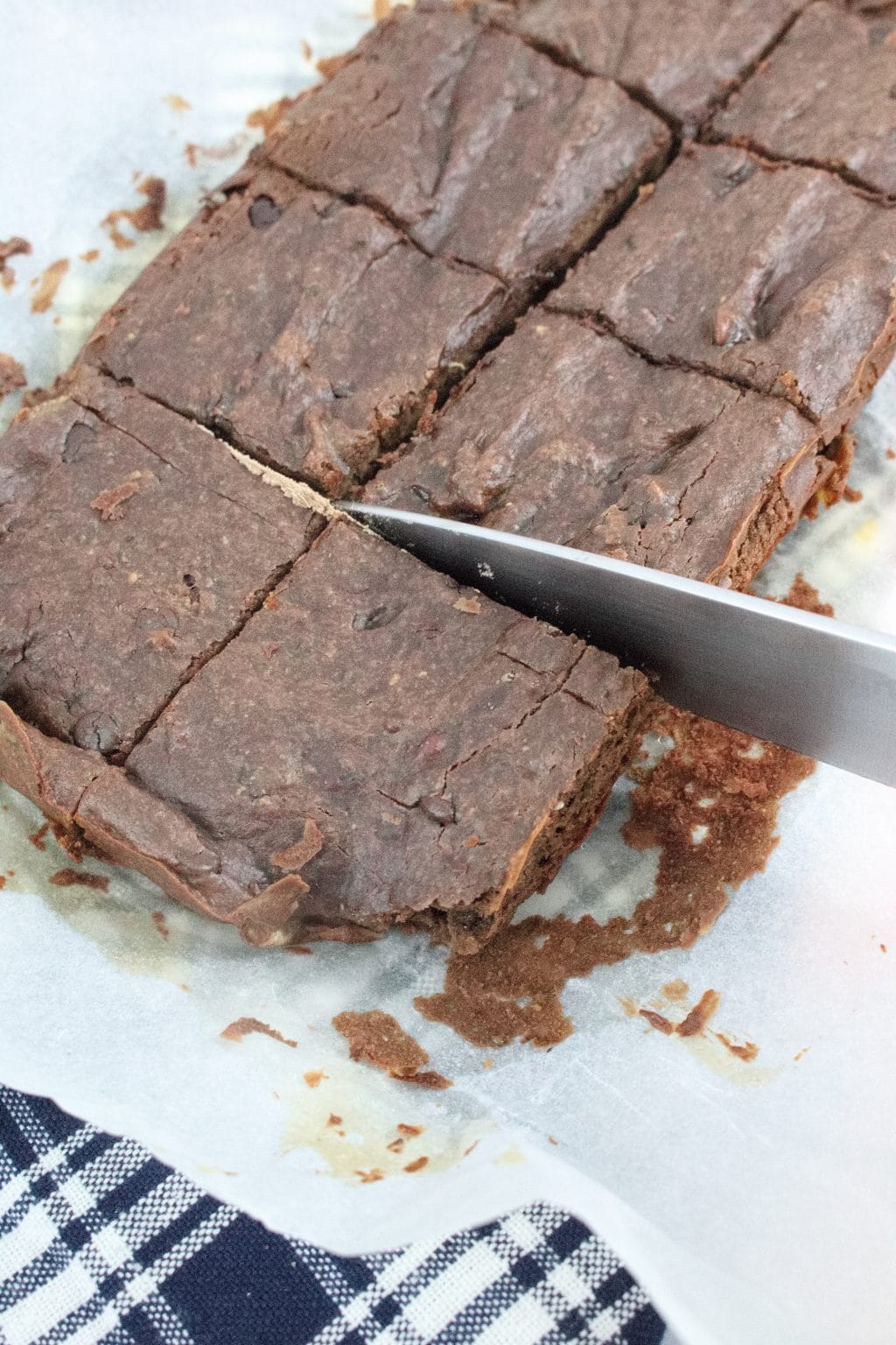Chocolate protein brownies on parchment paper being cut into squares
