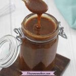 Pin image with text: small jar with lid attached filled with dark caramel sauce with a spoon pulling out and some sauce dripping off it