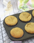 Peanut butter protein muffins in a dark grey muffin tray on a cooling rack with linen behind them
