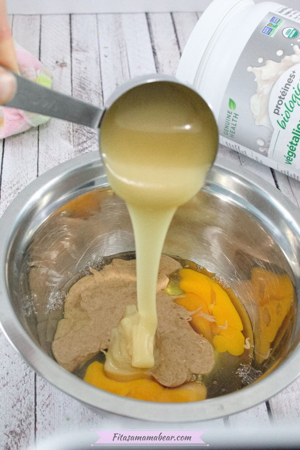 Honey being poured into a steel bowl with eggs and peanut butter