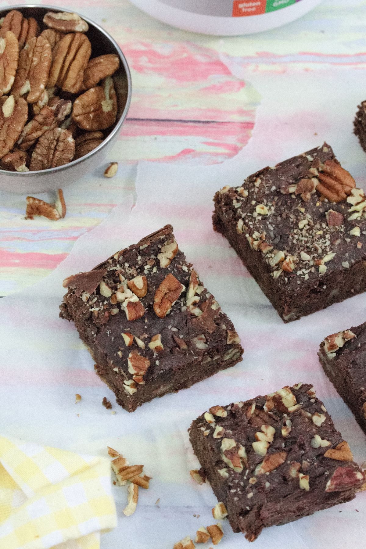 Chocolate protein brownies topped with pecans and cut into squares on parchment paper