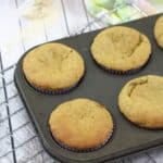 Peanut butter protein muffins in a dark grey muffin tray on a cooling rack with linen behind them