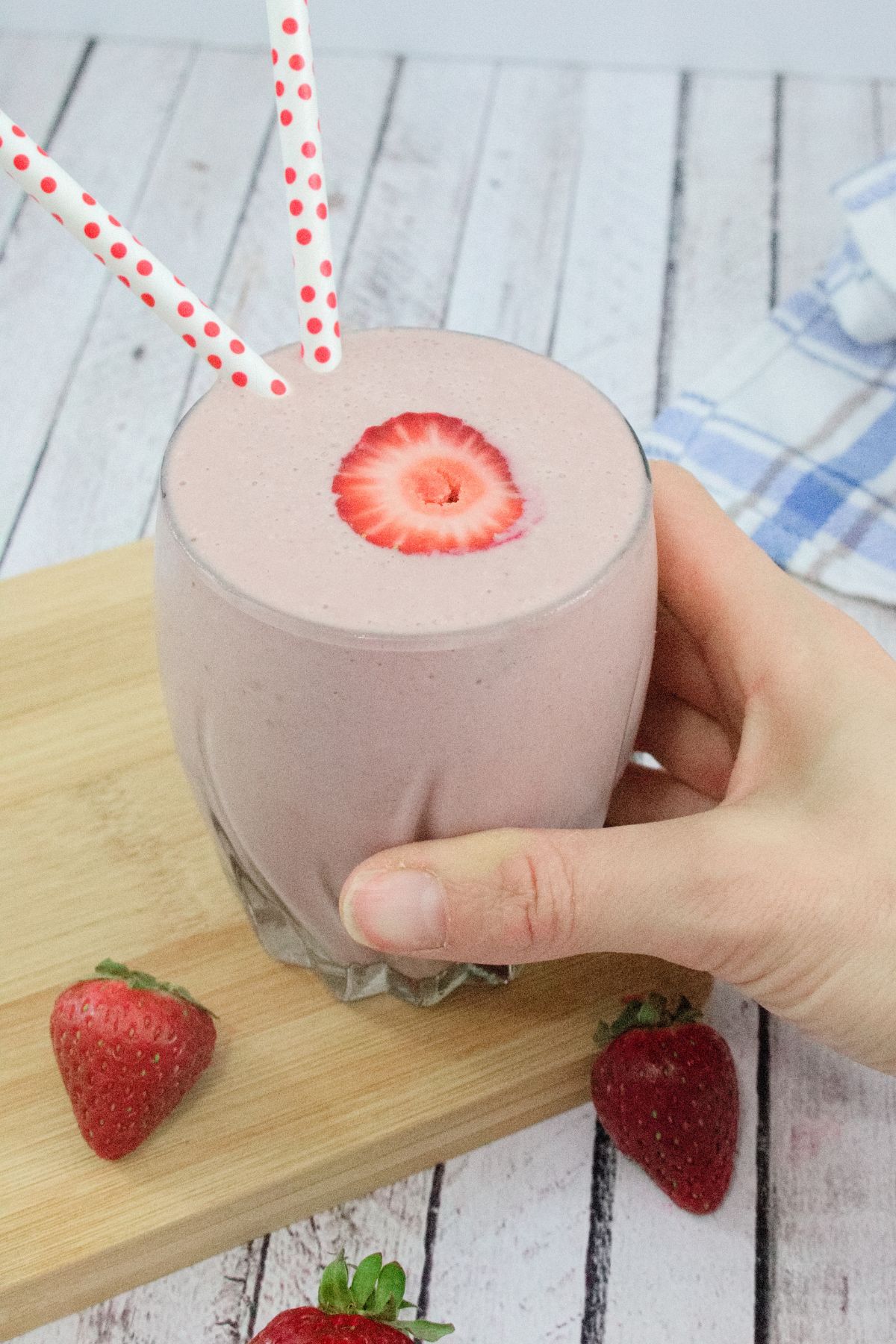 Strawberry protein shake on a wooden cutting board with berries around it.