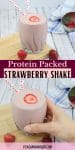 Pin image with text: two images of a high protein strawberry shake in a glass topped with polka dot straws and a sliced strawberry with glass on a cutting board, in the bottom image a hand holding the glass