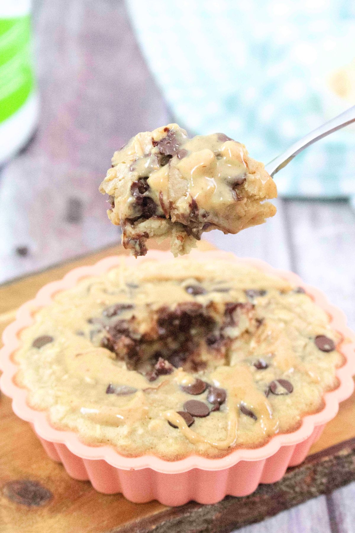 orange solicone mold on a cutting board with peanut butter chocolate chip baked oatmeal with a spoonful coming out and a blue linen behind it