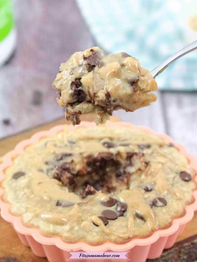 orange solicone mold on a cutting board with peanut butter chocolate chip baked oatmeal with a spoonful coming out and a blue linen behind it