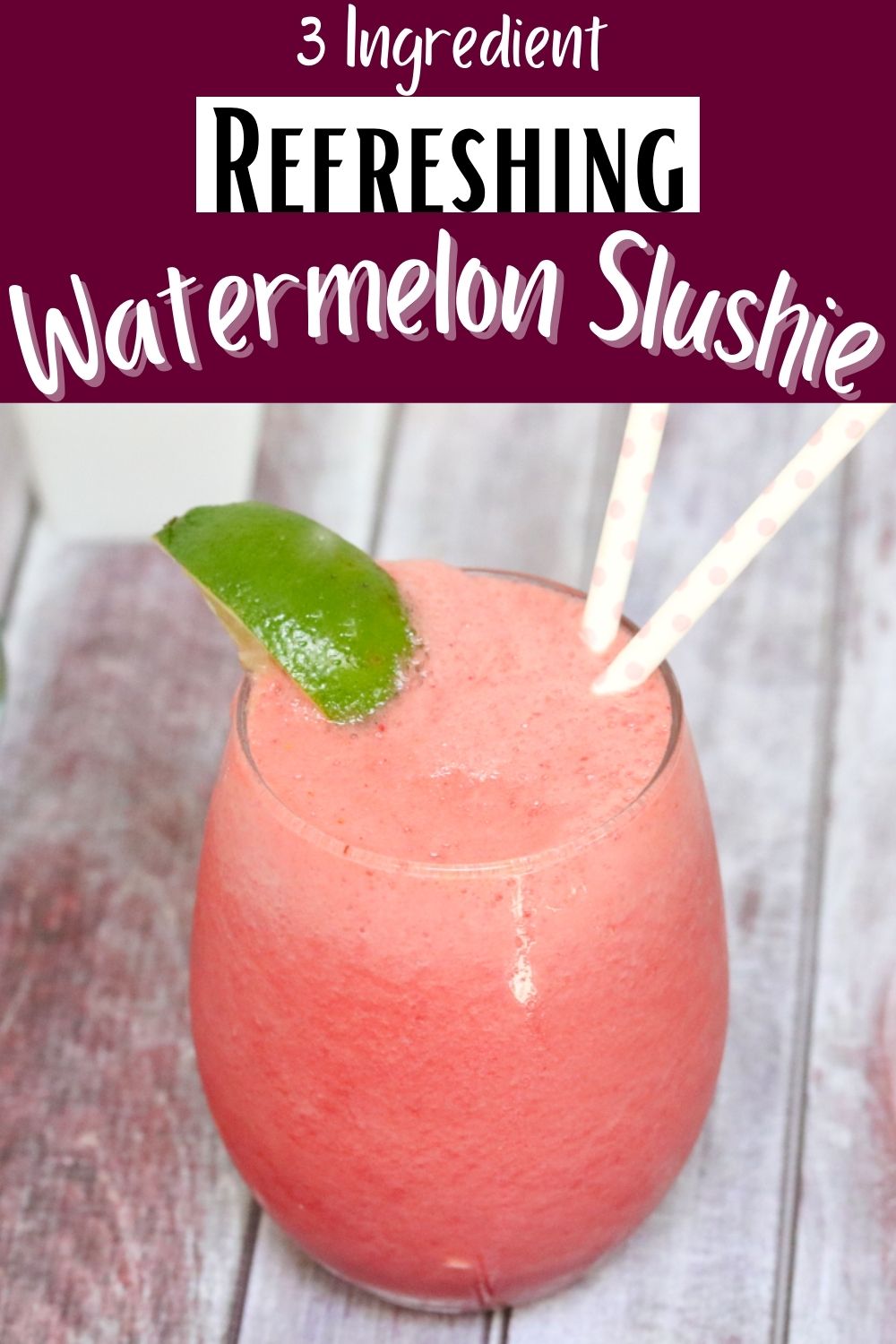 Pink watermelon slushie in a glass garnished with lime and more watermelon and lime behind it