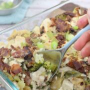 A casserole with bacon and broccoli with a spoon scooping some out
