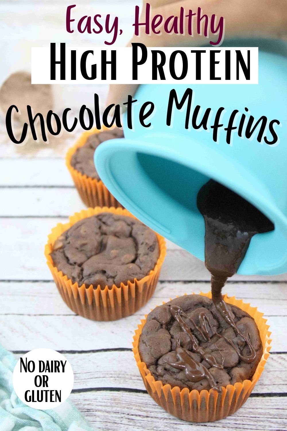Pin image with text about chocolate protein muffins: Blue silicone pot pouring melted chocolate onto a chocolate protein muffin in an orange muffin liner with more muffins behind it
