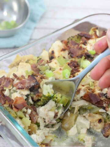 A casserole with bacon and broccoli with a spoon scooping some out