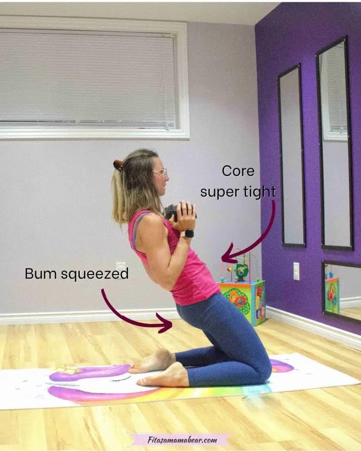woman in pink shirt and blue pants on her knees holding a dumbbell at chest height and leaning back with arrows and text about performing the exercise