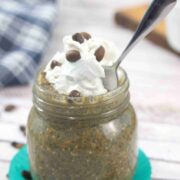 Mason jar with coffee chia pudding topped with dairy-free whipped cream and a spoon in the jar