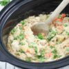 Wooden spoon scooping our dairy-free chicken pot pie from a slow cooker.
