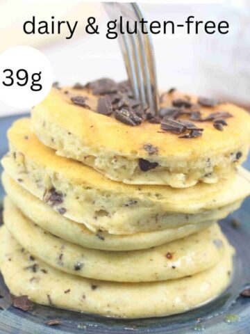 Fork sticking into a stack of protien pancakes with chocolate on top on a blue plate.