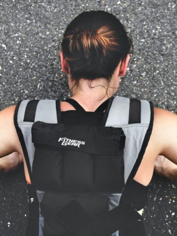 Woman with a weighted vest on doing push ups.