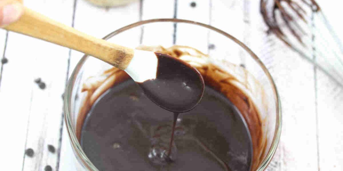 Dairy-free chocolate glaze in a glass bowl with a white spoon.