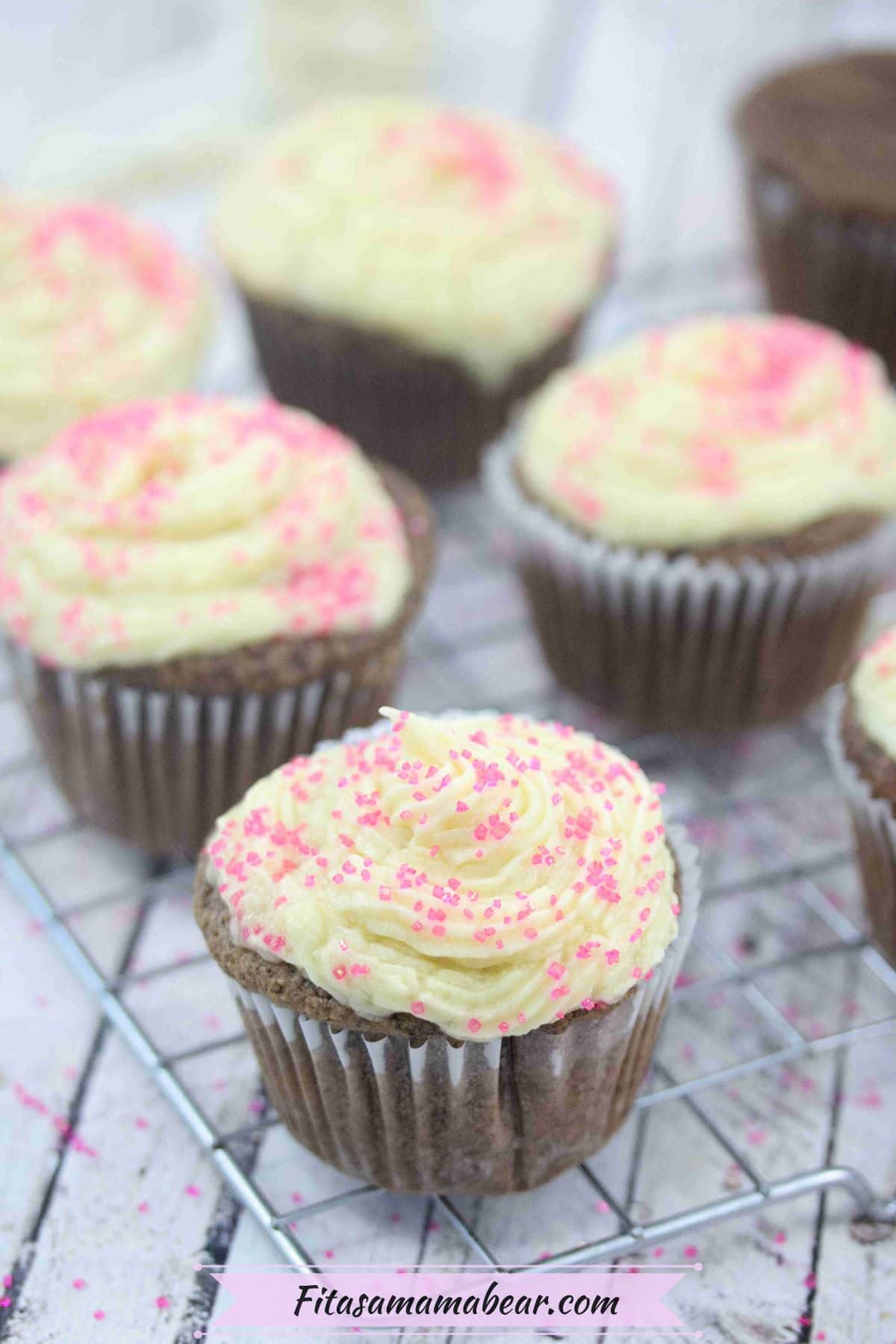 Chocolate protein cupcakes topped with vanilla buttercream frosting with pink sprinkles.