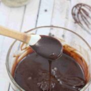 Dairy-free chocolate ganache dripping off a white spoon over a glass bowl.