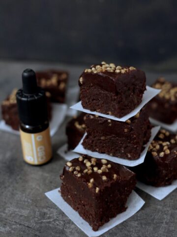 Brownies with peanuts on top separated by parchment paper.