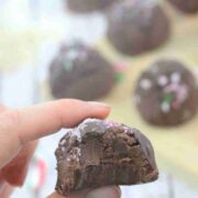 Close up of a chocolate protein truffle with a bit out of it held between two fingers.