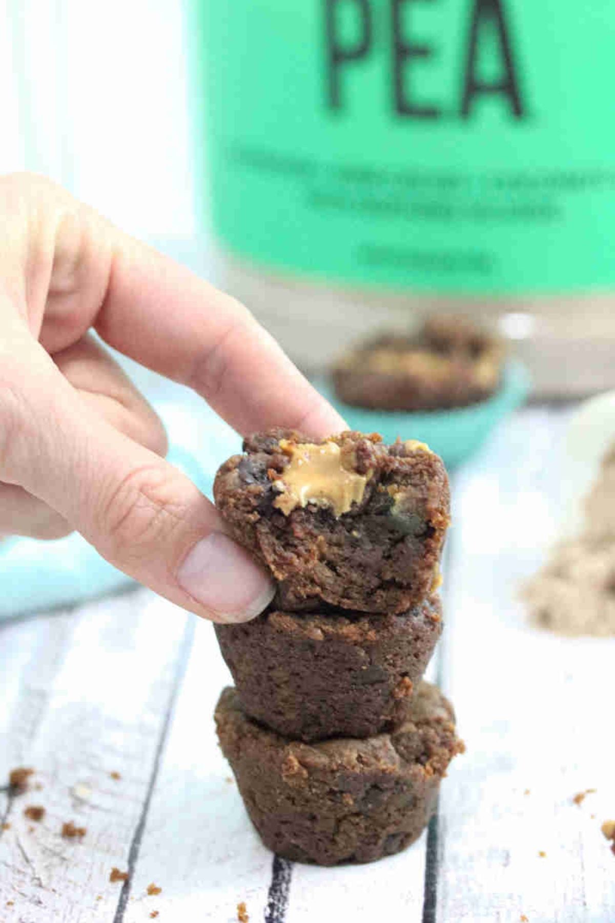 Three chocolate protein brownies topped with whole30 whipped cream and sprinkled with chocolate powder.