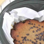 Black slow cooker lined with parchment paper and high protein banana bread with chocolate chips in it.