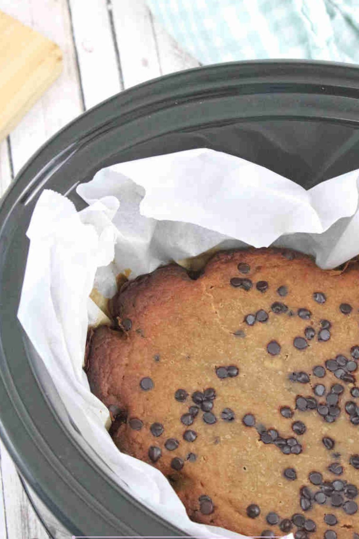 Black slow cooker lined with parchment paper and high protein banana bread with chocolate chips in it.