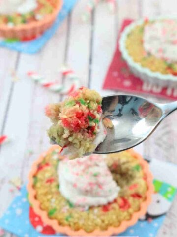 Candy cane baked oatmeal with coconut whipped cream in a orange mold on a blue napkin with a spoonful of the oatmeal held above it.
