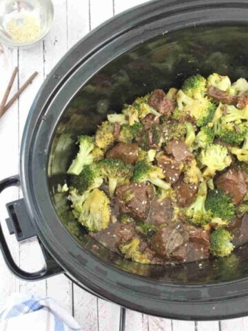 Black slow cooker with beef and broccoli in it.