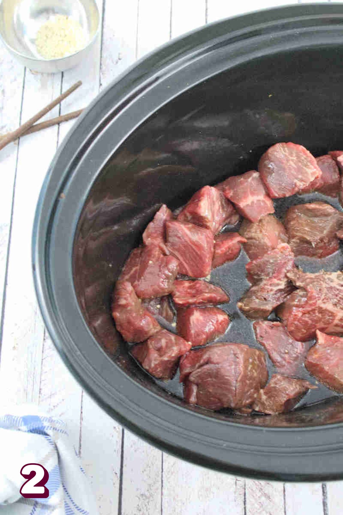 Chunks of beef in a soy sauce in a black slow cooker.